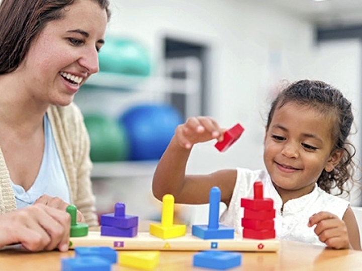 Teacher and young child playing with blocks