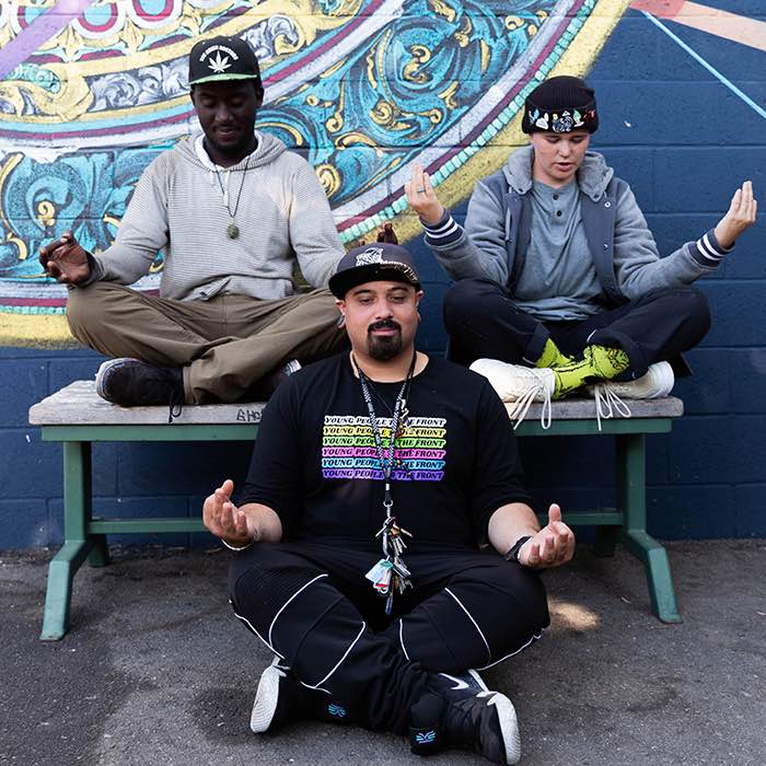 men practicing yoga in front of an urban mural