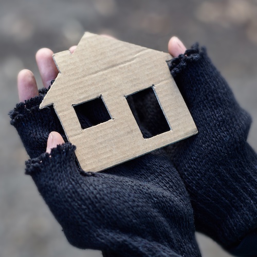 Photo of hands holding a piece of cardboard cut to look like a house