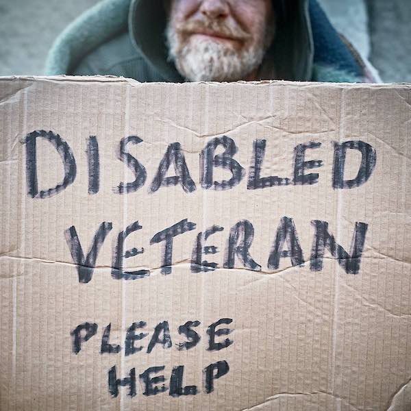 homeless person holding cardboard sign