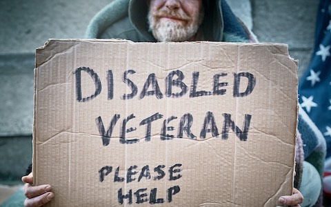 homeless person holding cardboard sign