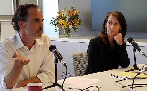 Two people talking at a table with mics