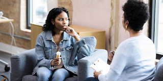 Young woman holding pill bottle meets with substance use counselor