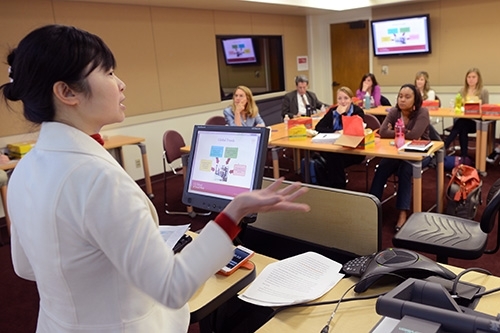 Professor standing at the front of a classroom talking to students