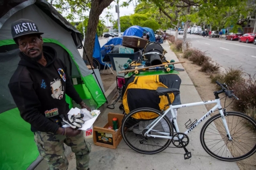 A man gathers his belongings before an L.A. sanitation crew arrives at an encampment. 