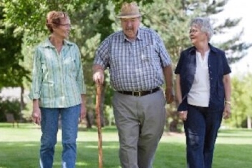 Three elderly people walking together in a field