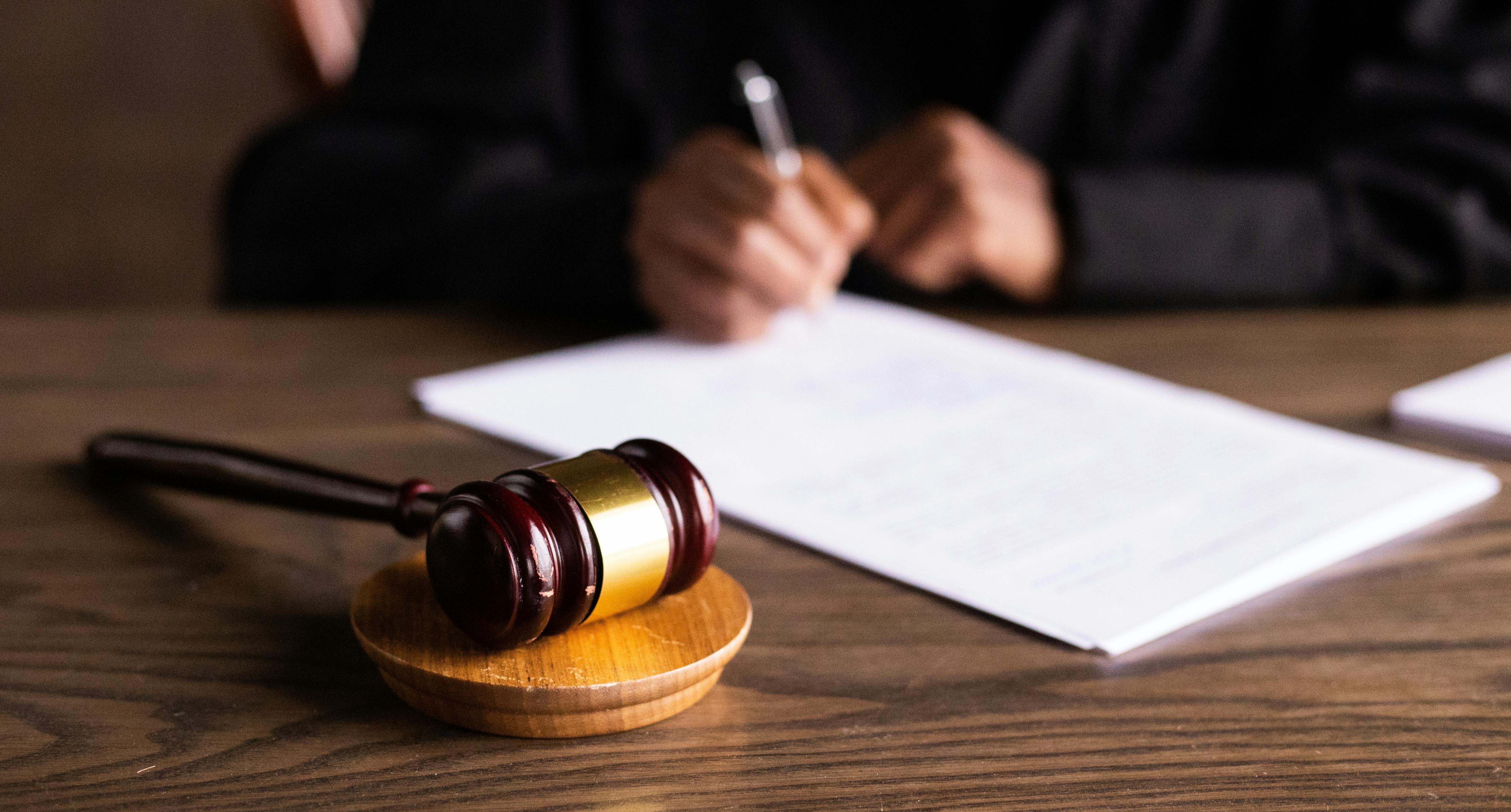 image of a gavel and hands signing a document