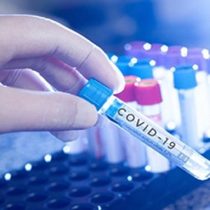 Lab worker handling test tube labeled "COVID-19"