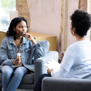 Young woman holding pill bottle meets with substance use counselor