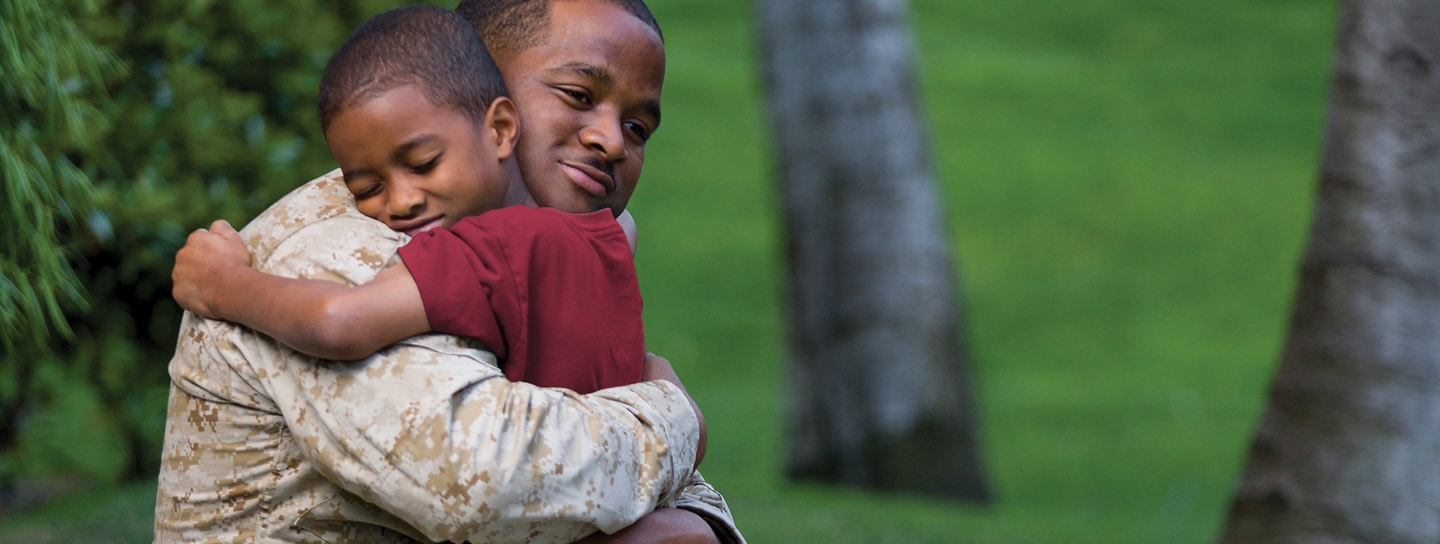 Military man embracing child